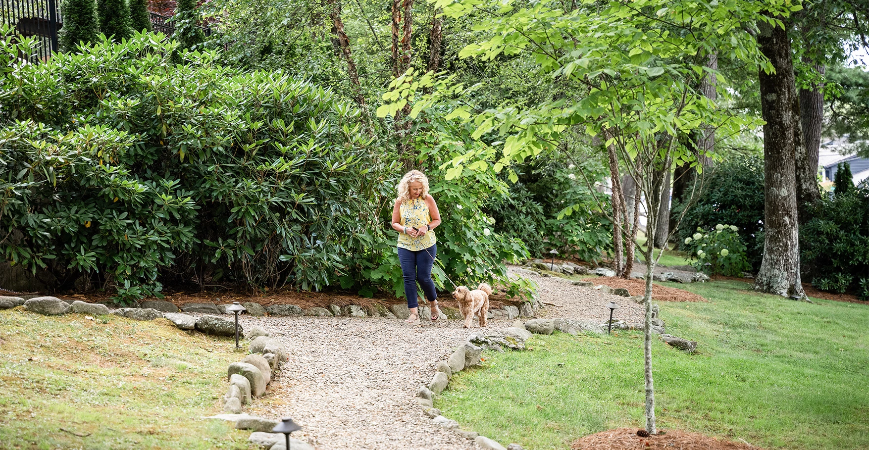a woman walking a dog on a path