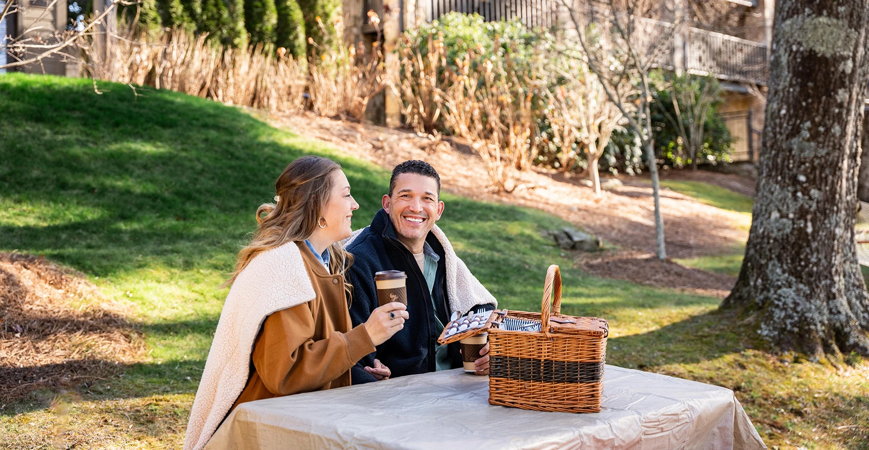 a man and woman sitting at a table with a picnic basket and a basket
