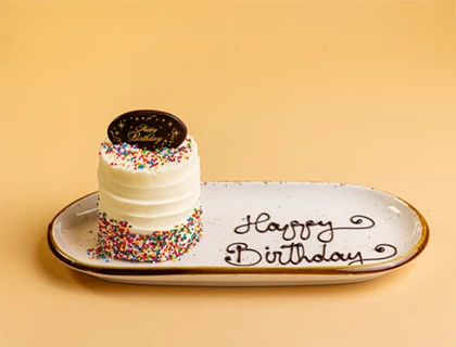 a white cake with sprinkles on a white rectangular plate