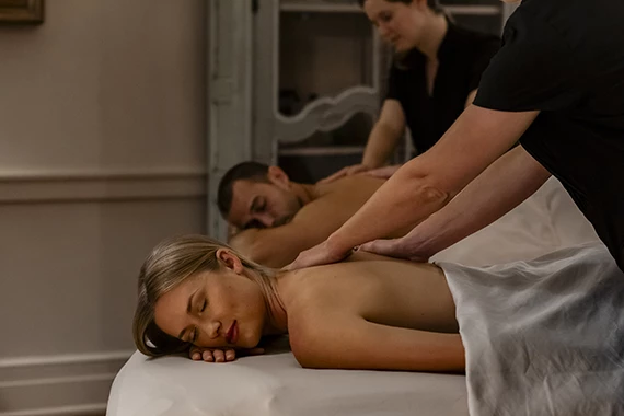 a woman lying on a bed with a man and a woman in the background