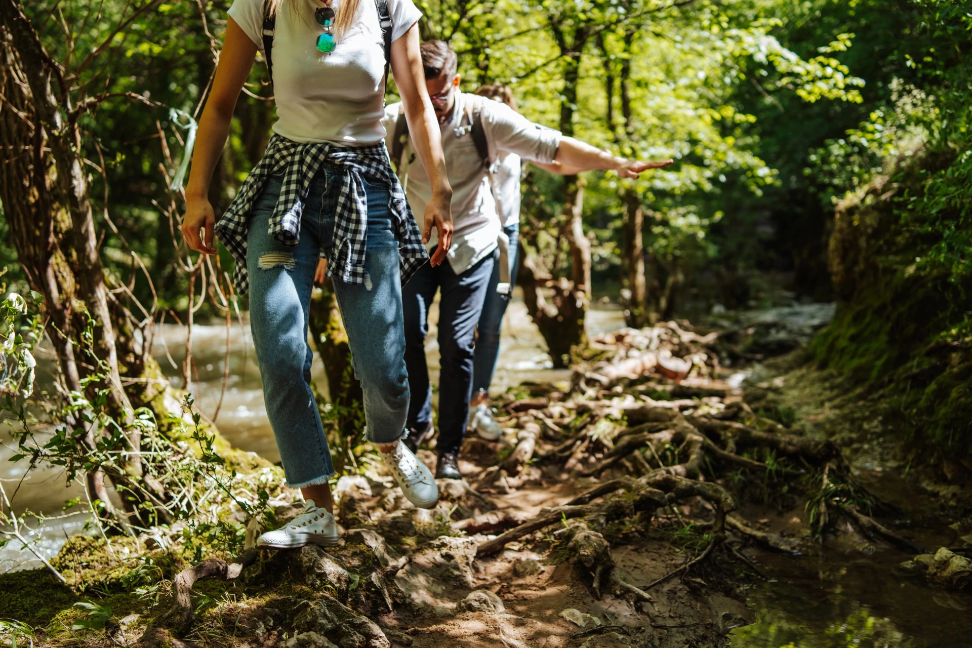 a man and woman walking on a trail in the woods