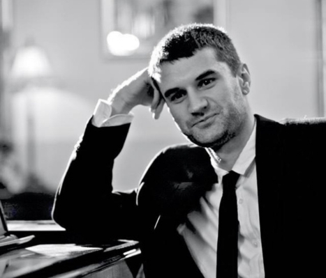 a man in a suit leaning on a piano