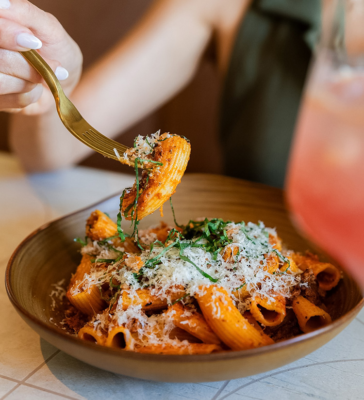 a person holding a fork over pasta