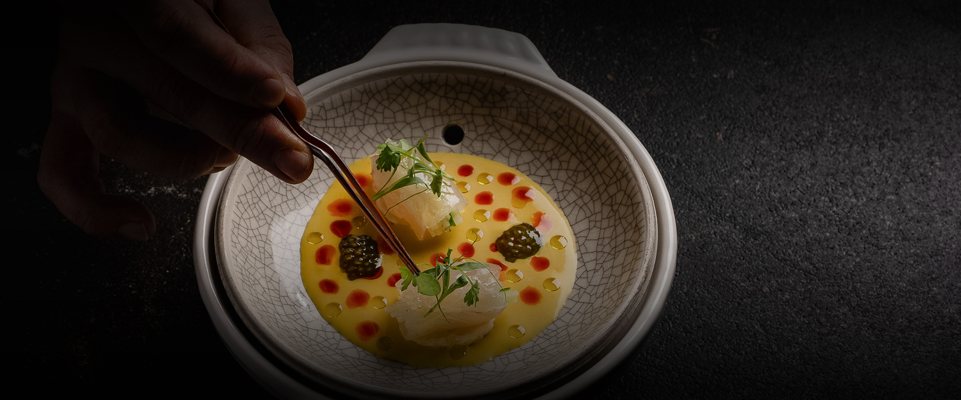 a person holding a pair of tongs in a bowl of food