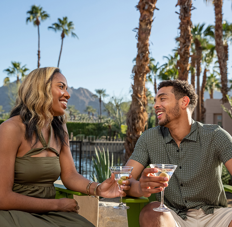 a man and woman sitting on a bench with drinks