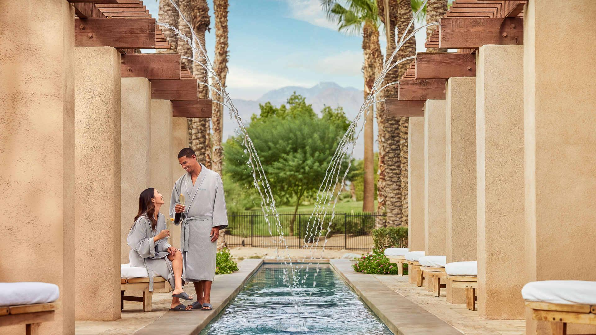 a man and woman in bathrobes standing next to a pool of water