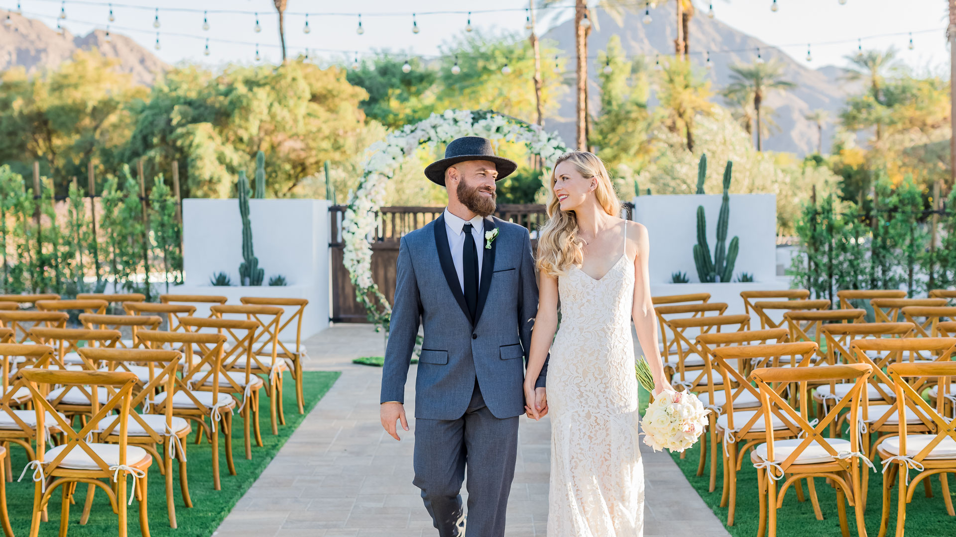 a man and woman holding hands and walking down a path