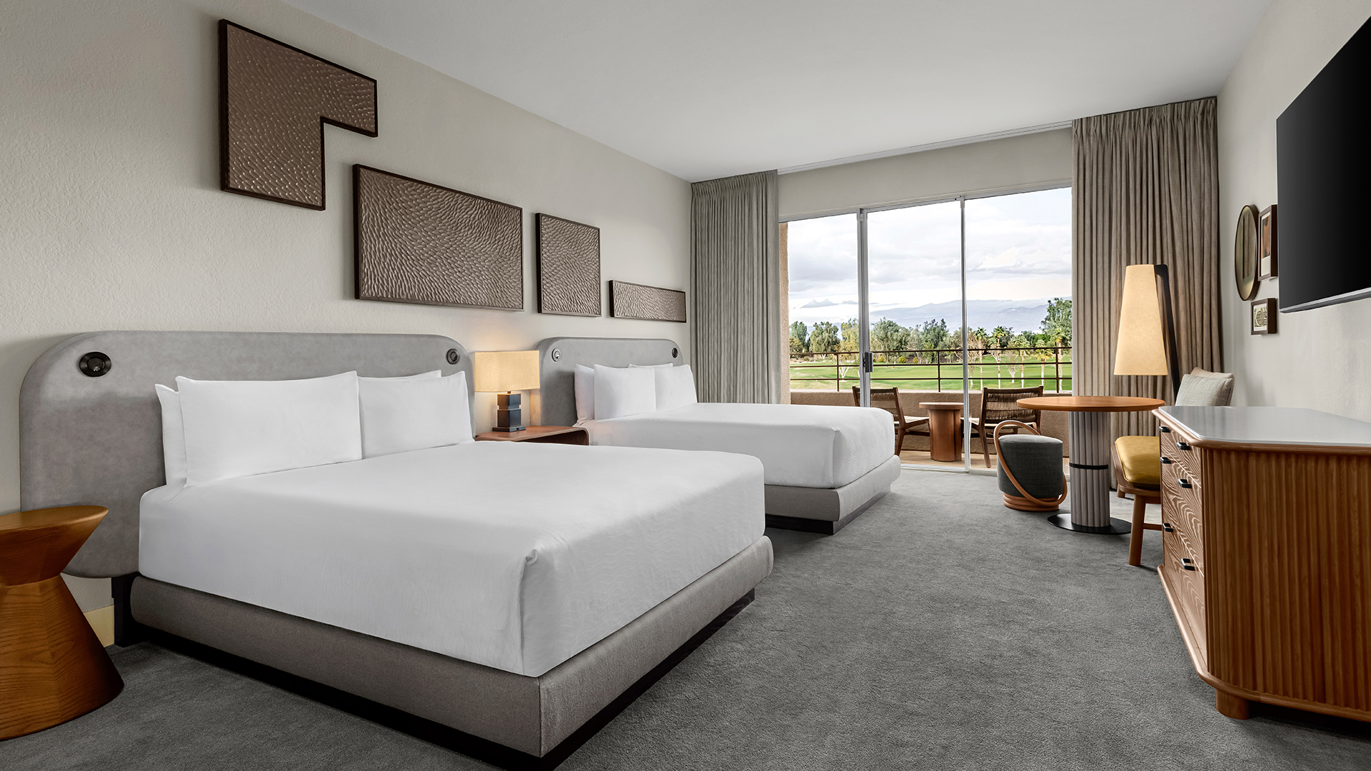 a room with two beds and a table with a view of golf course