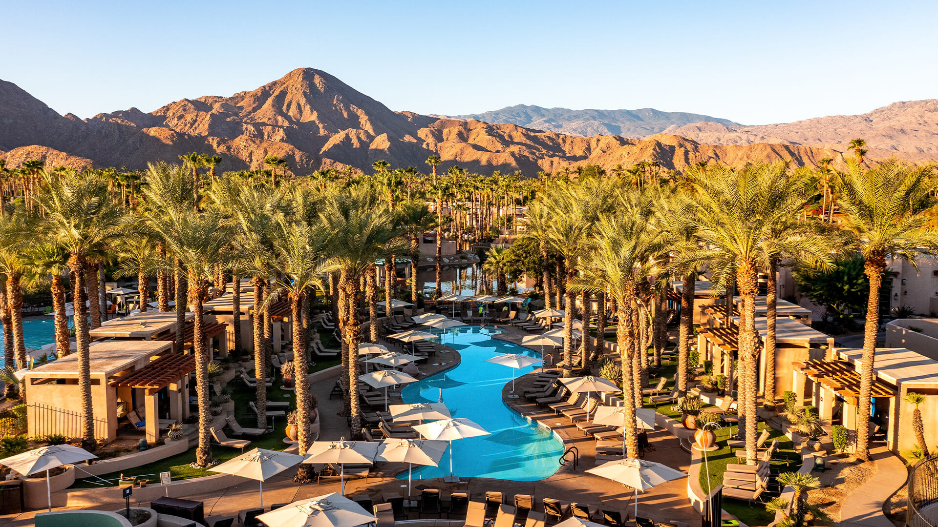 a pool with palm trees and mountains in the background