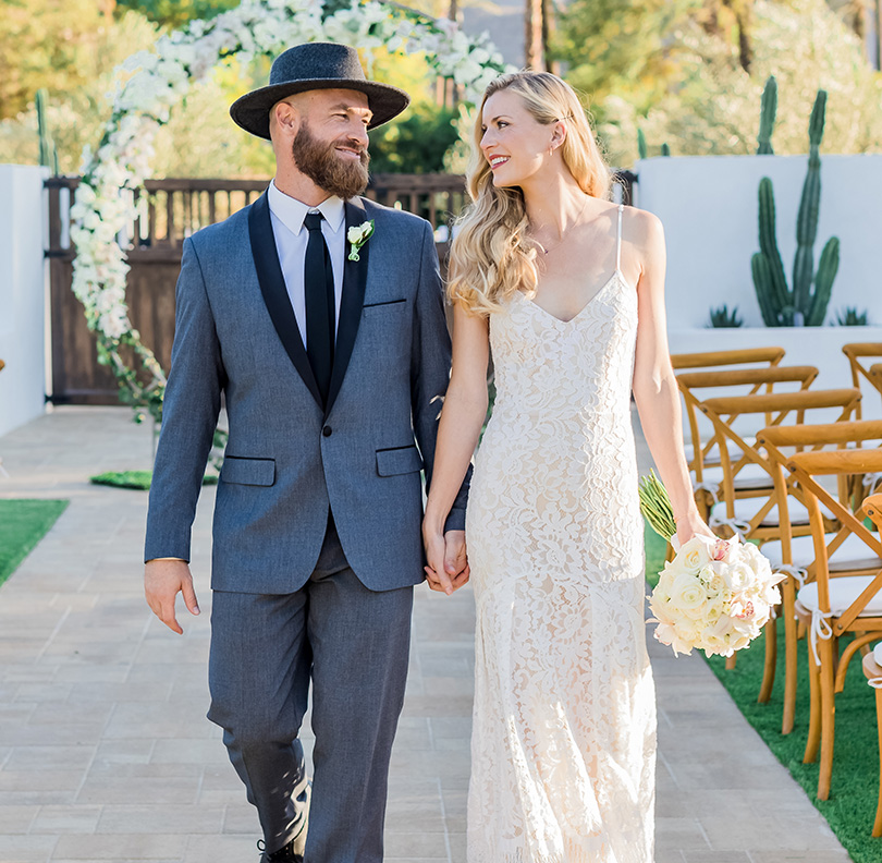 a man and woman holding hands and walking down a path