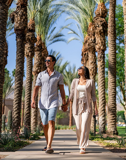 a man and woman holding hands and walking on a sidewalk
