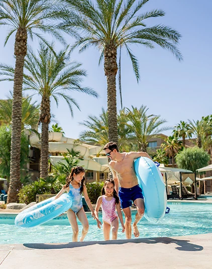 a man and two girls running into a pool