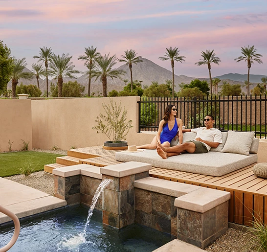 a man and woman sitting on a couch in a backyard