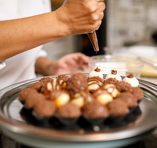 a person putting chocolate on a plate of desserts