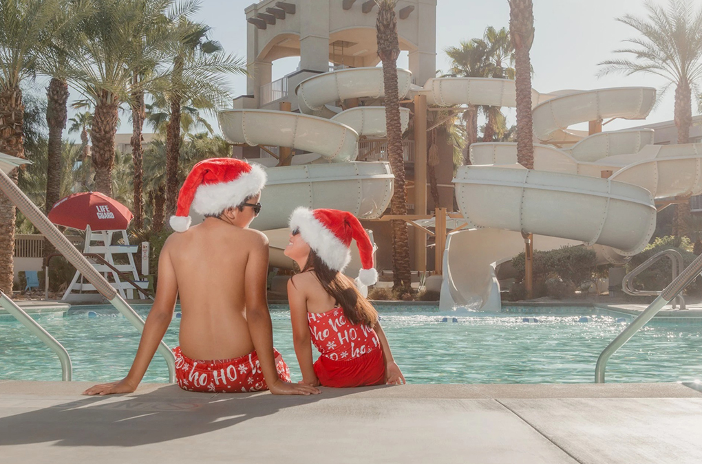 two people sitting in a pool wearing santa hats