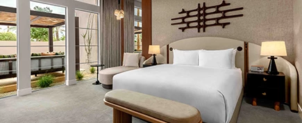 a bed with white sheets and a bench in a room