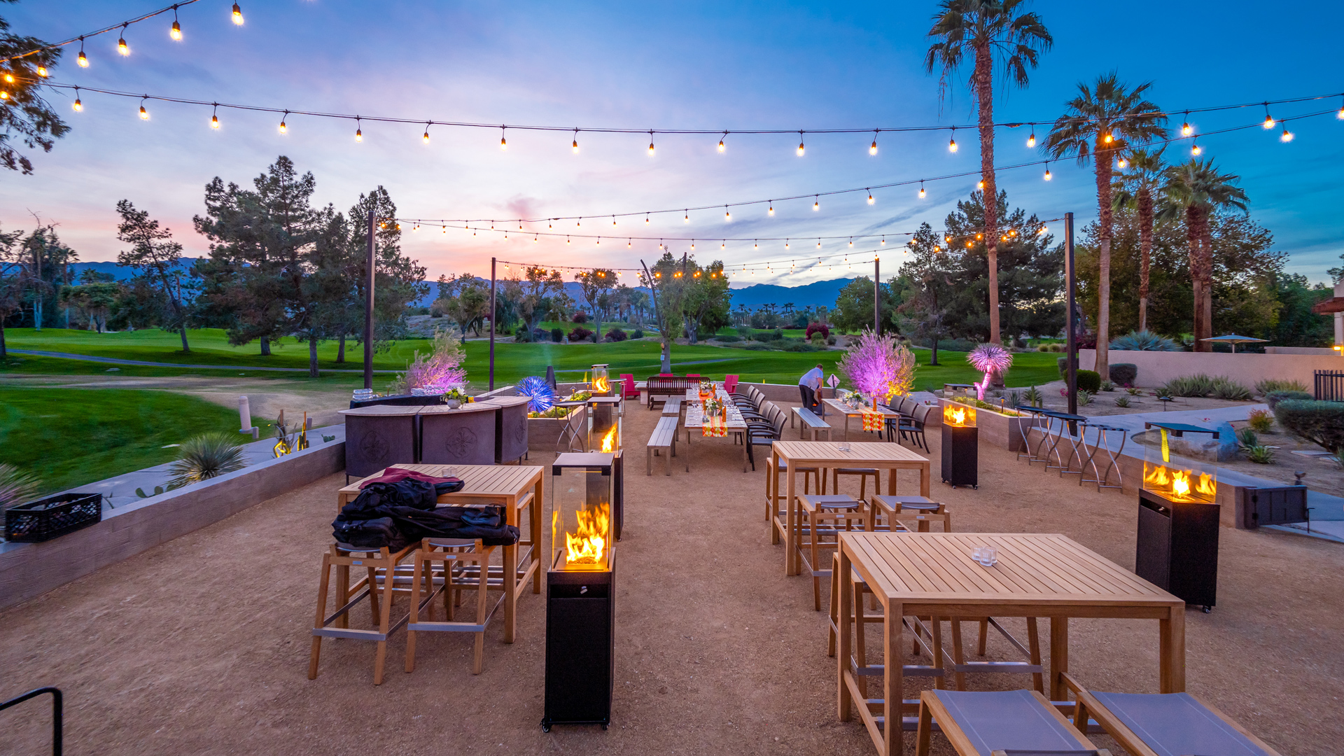 a outdoor patio with tables and chairs and lights