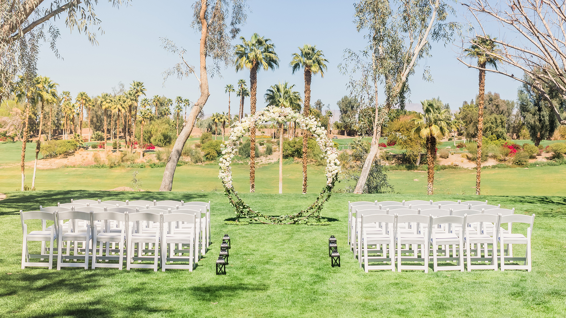 a circular arch with white chairs and white chairs in a grassy area
