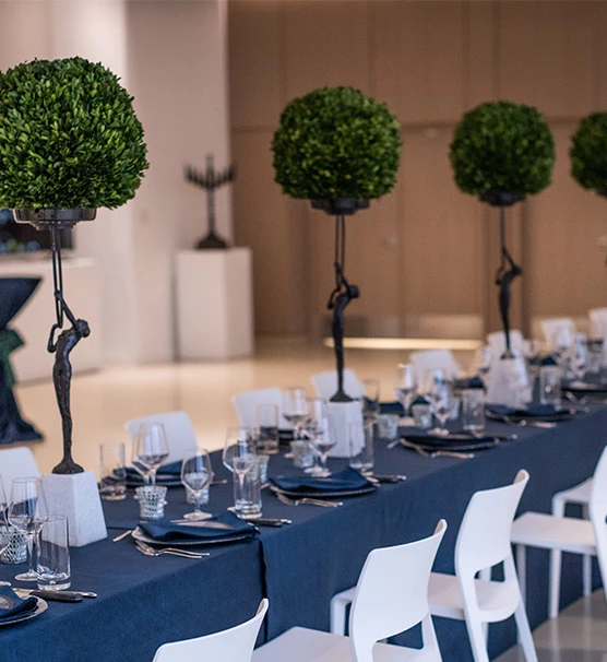 blue wedding reception table with tiny men holding up greenery in the middle of the table