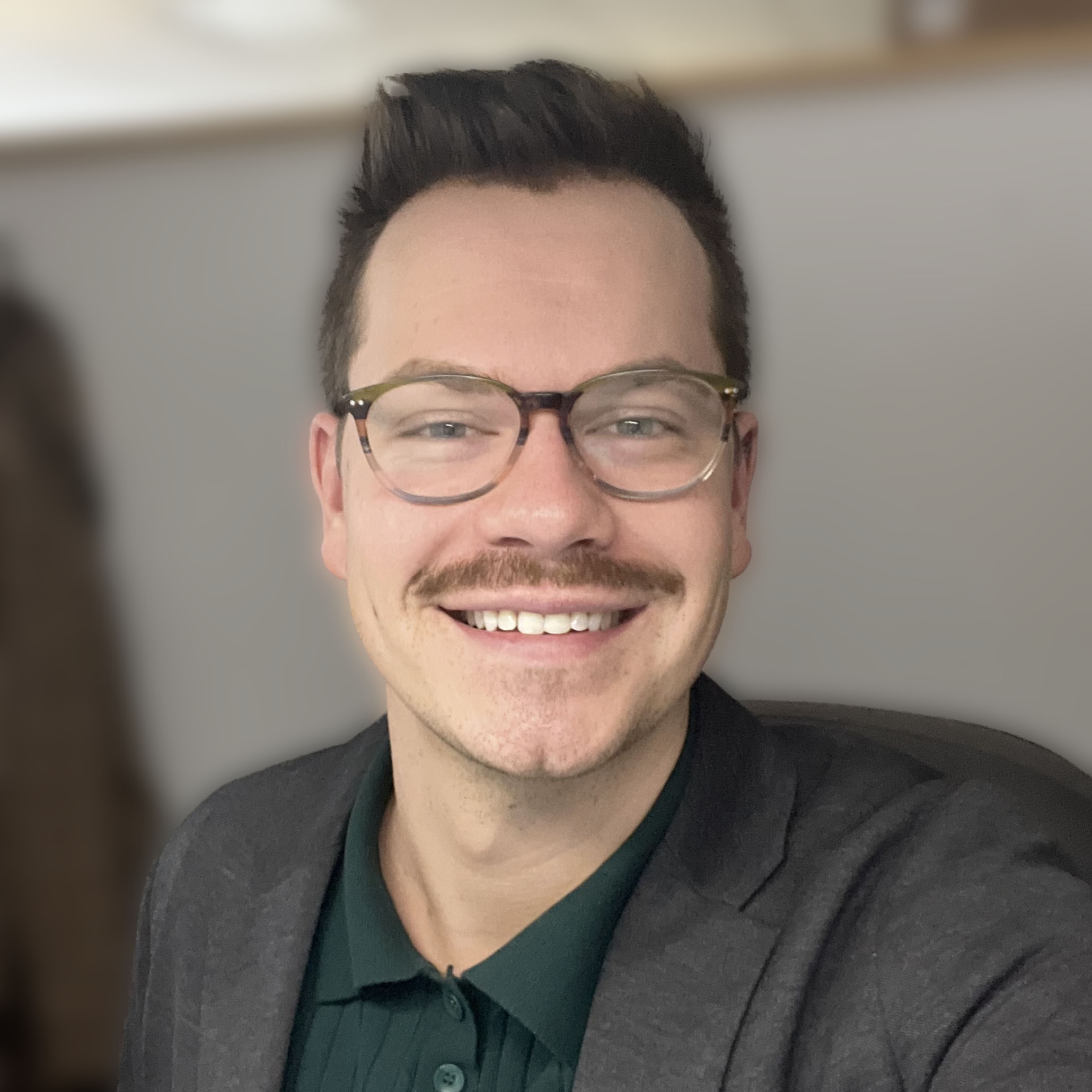 a man with mustache wearing glasses and a suit