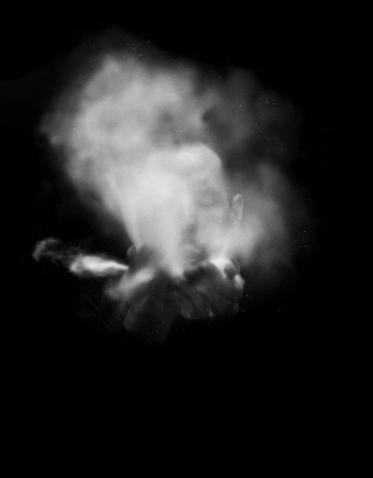 a black and white image of a person's hand with smoke
