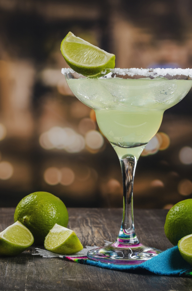 a glass with a drink and limes
