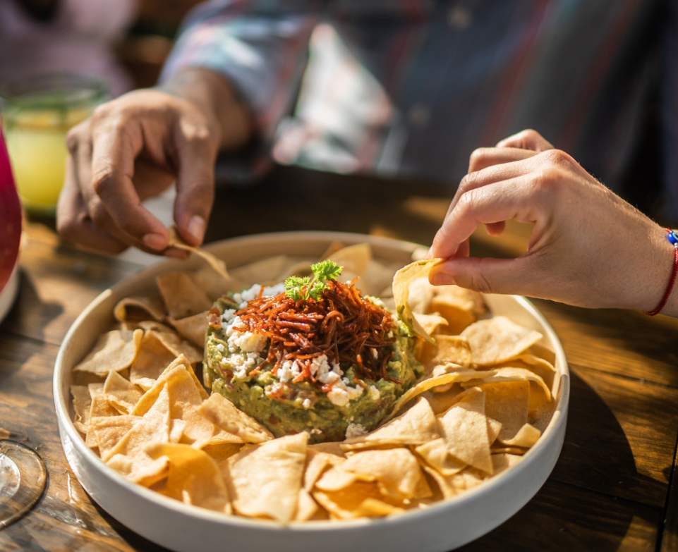 a person dipping a chip into a bowl of chips