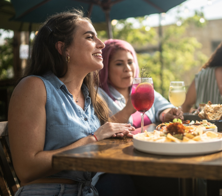 a group of women sitting at a table with food and drinks