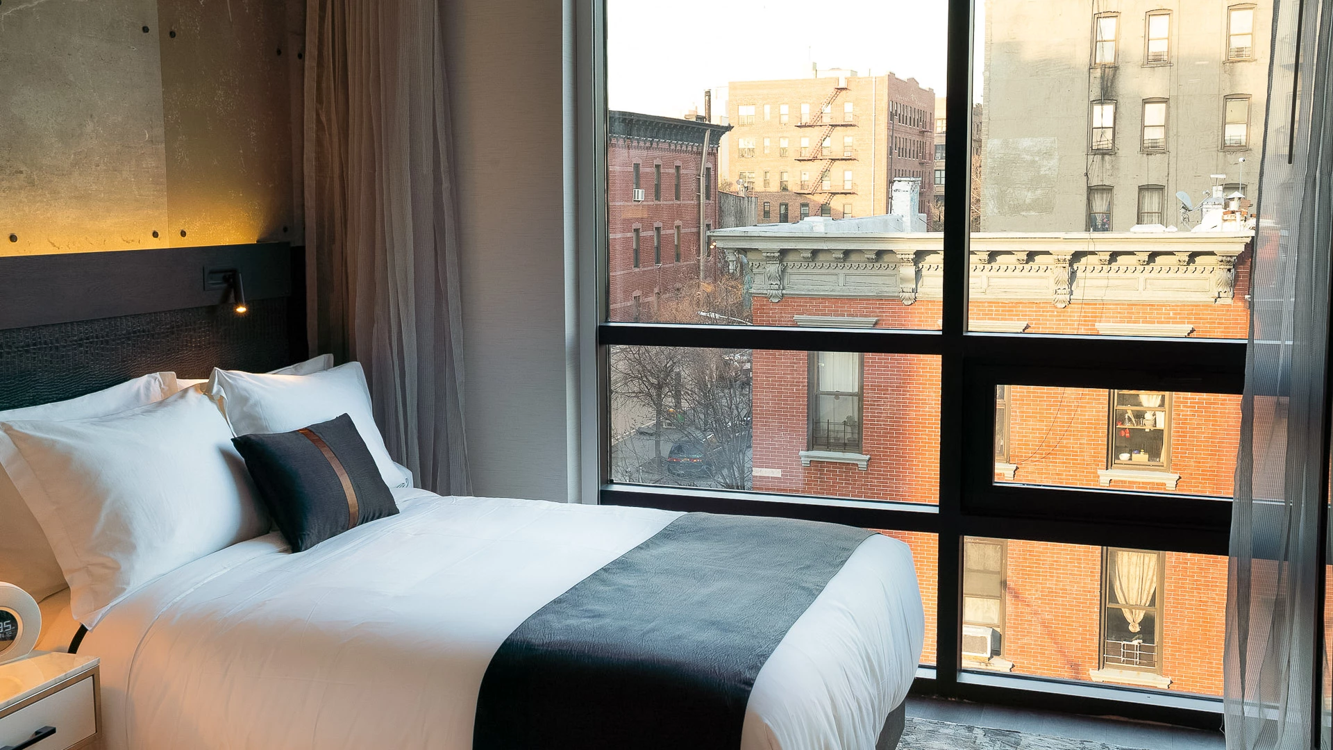 A hotel room with a bed, window, and city view.