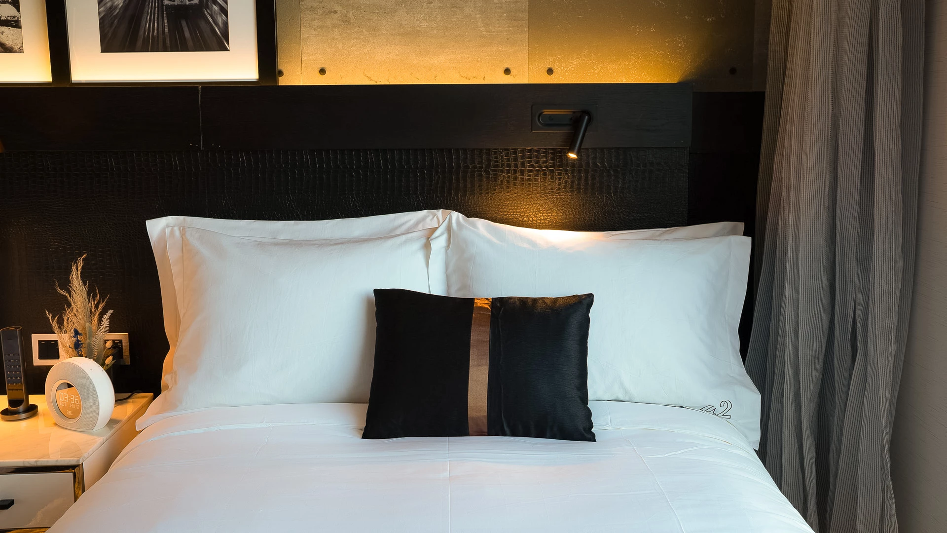 A neatly made bed with white bedding and a black headboard