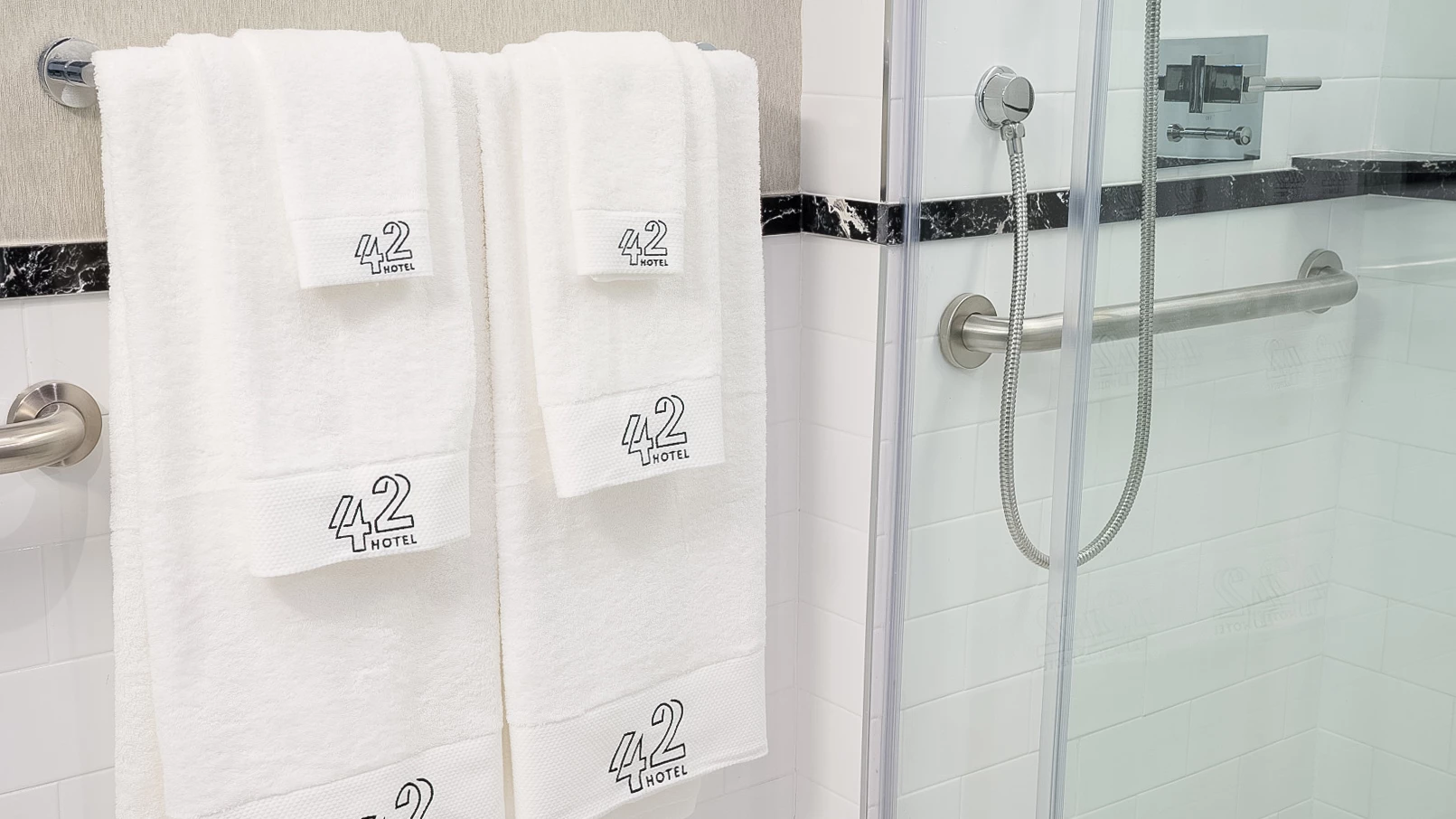 A bathroom with white towels hanging on a rack and a shower with a glass door.