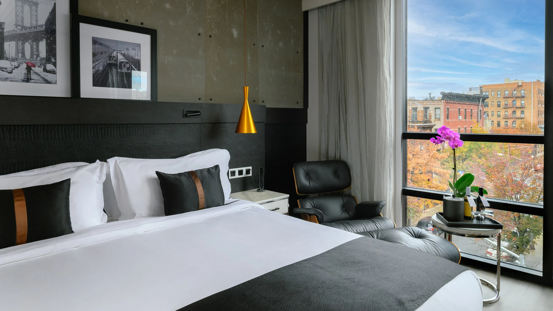 A hotel room with a large bed, window, chair, and table with a plant.