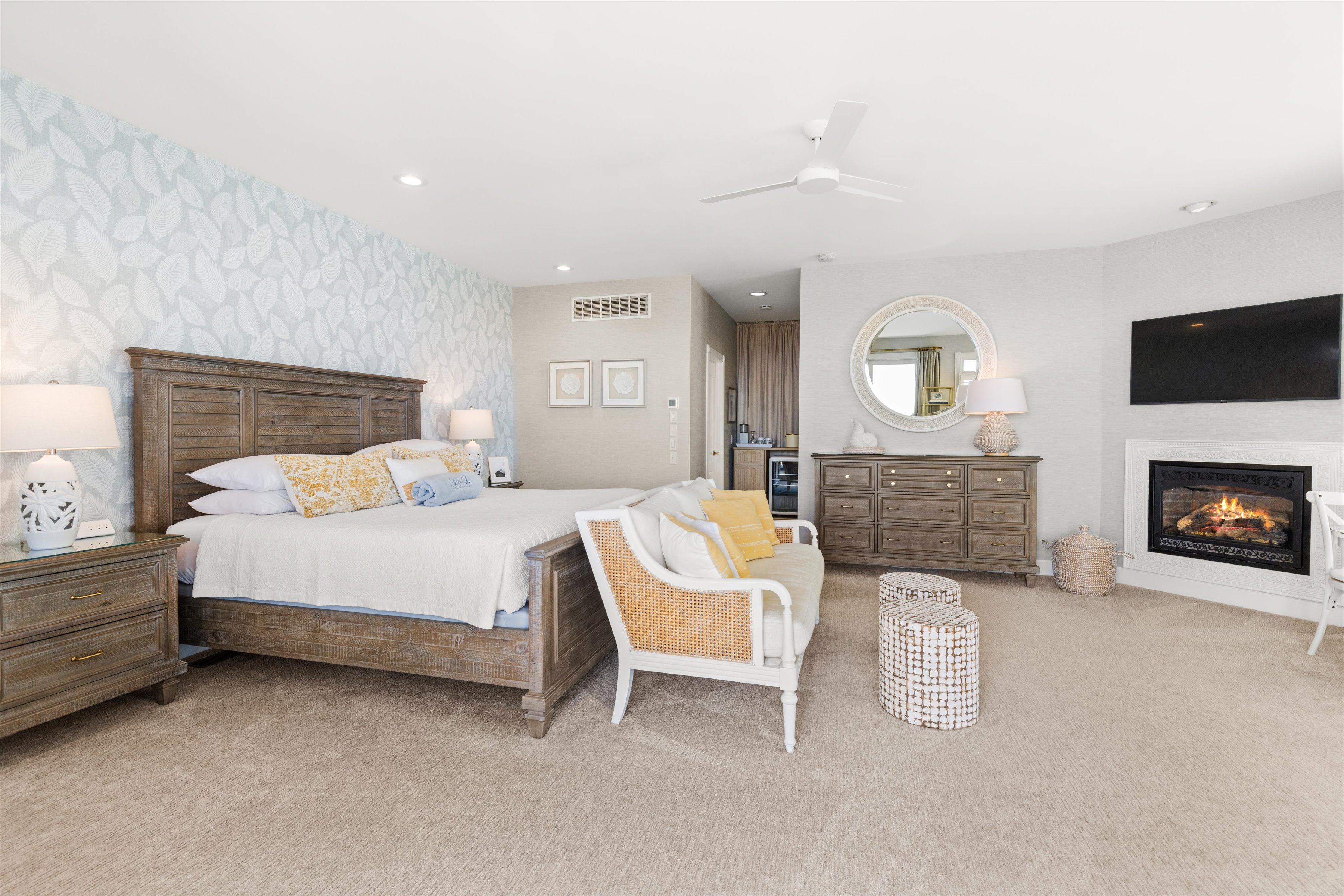 A wide view of a guest room with a bed, fireplace, and TV.