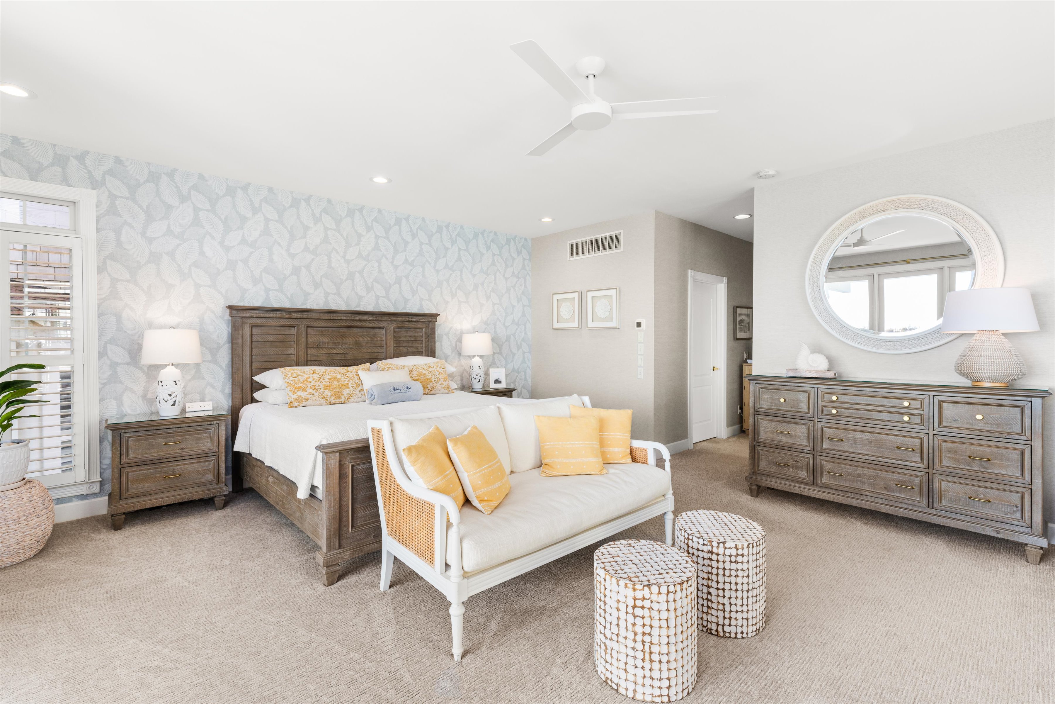 A wide view of a guest room with a bed, dresser, mirror, sofa, and nightstands.