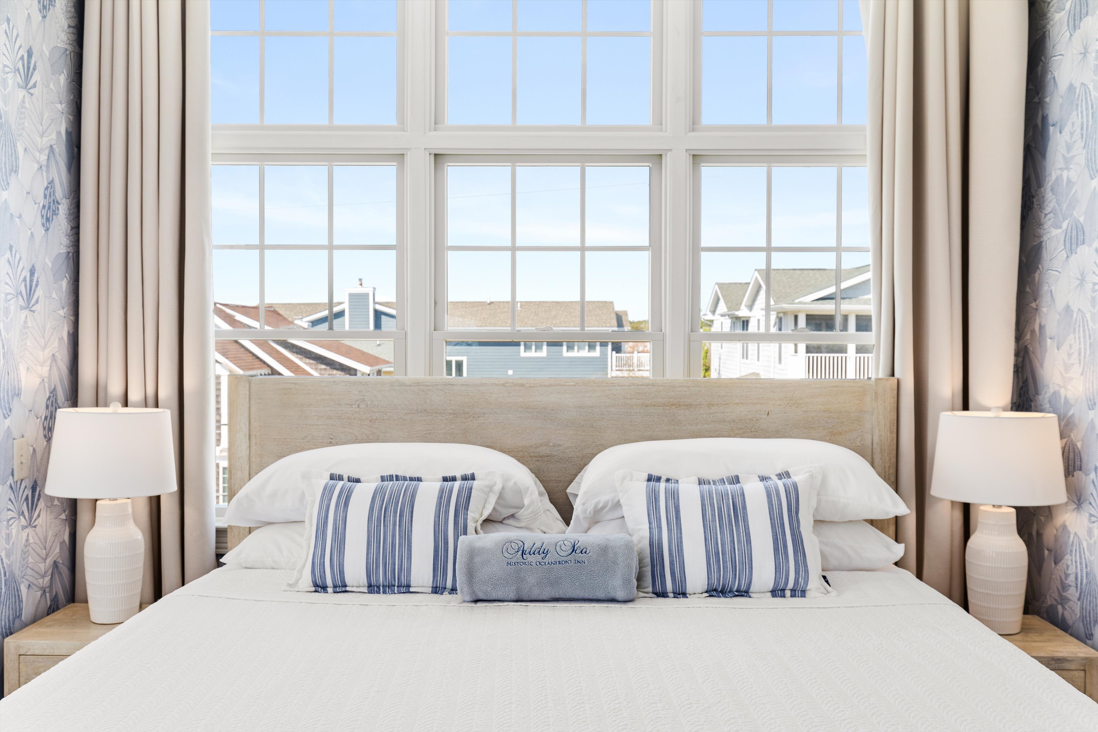 A neatly made bed with a large window behind it.