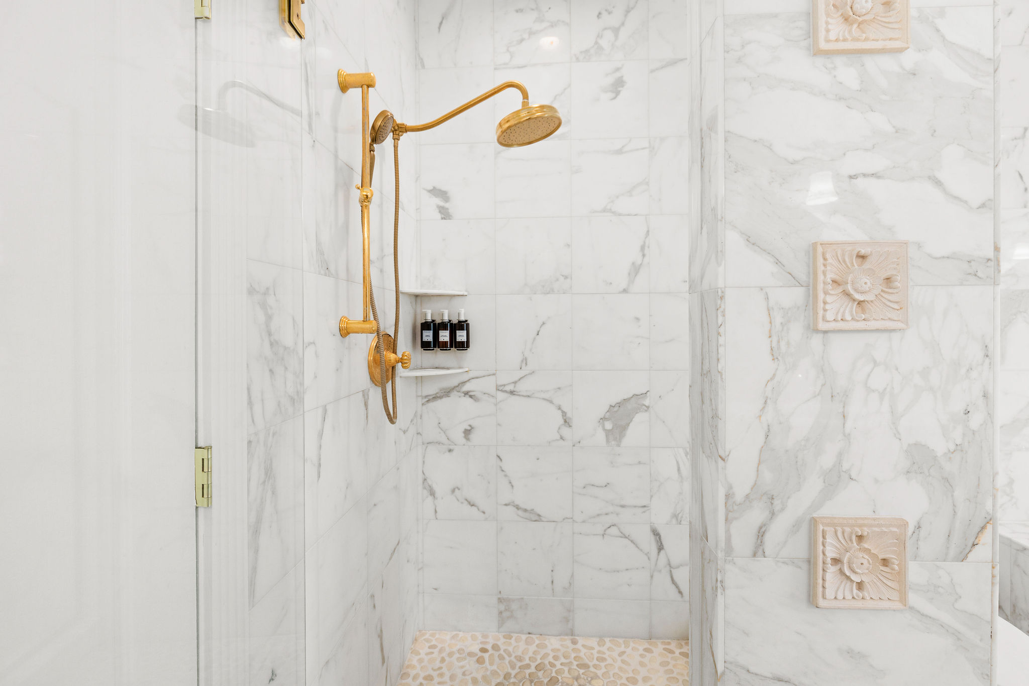 A luxurious shower with marble tiles and gold fixtures.