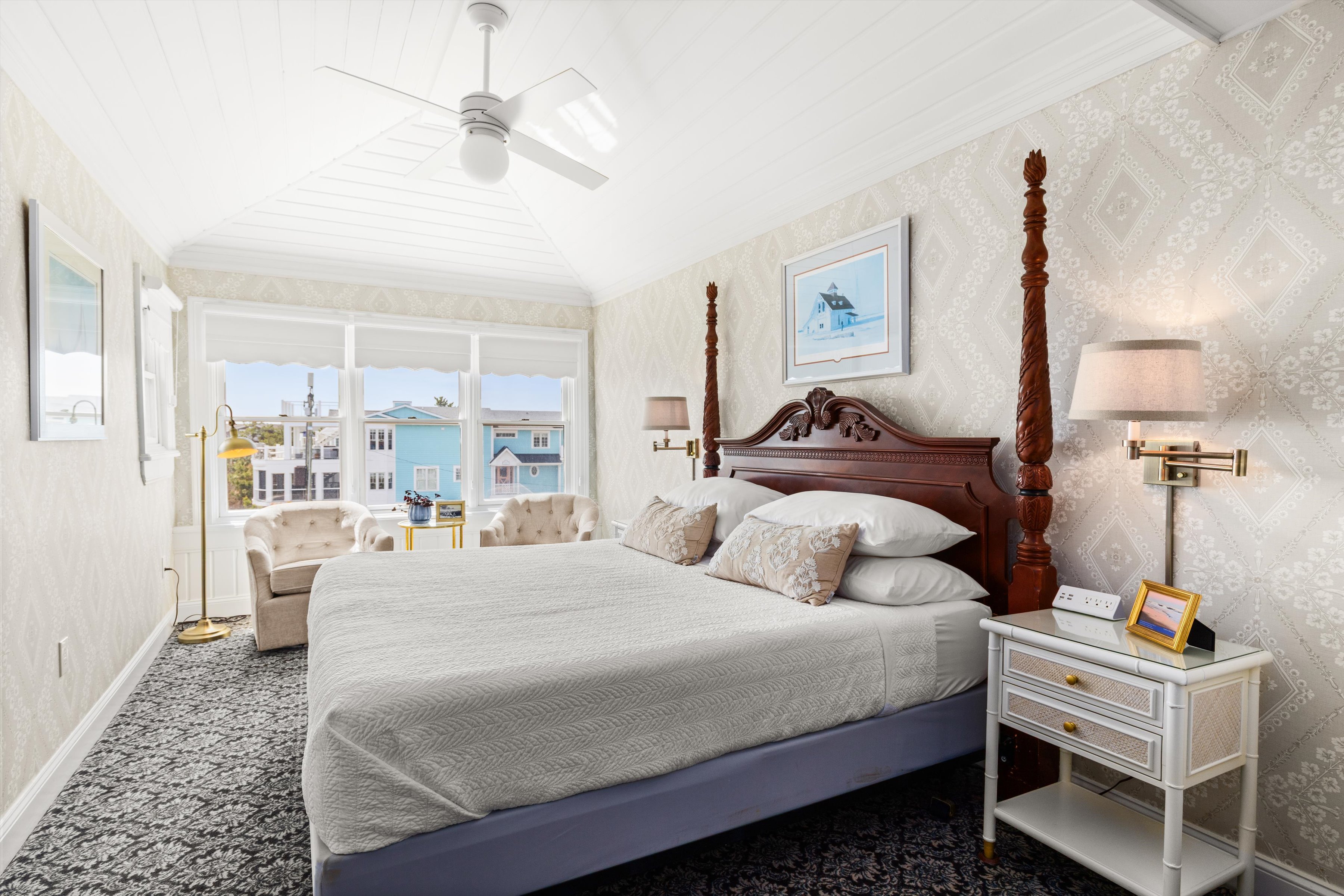A large, well-lit hotel room with a king-sized bed, two nightstands, and a window with a view.
