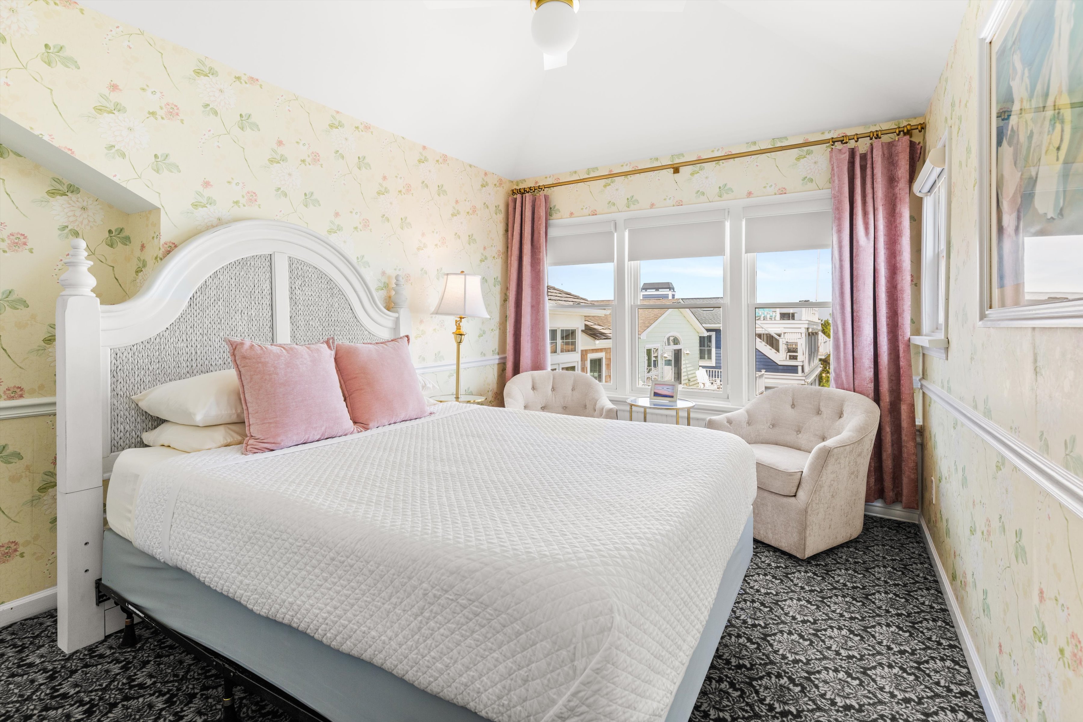 A wide view of a guest room with a large bed, armchair, and window