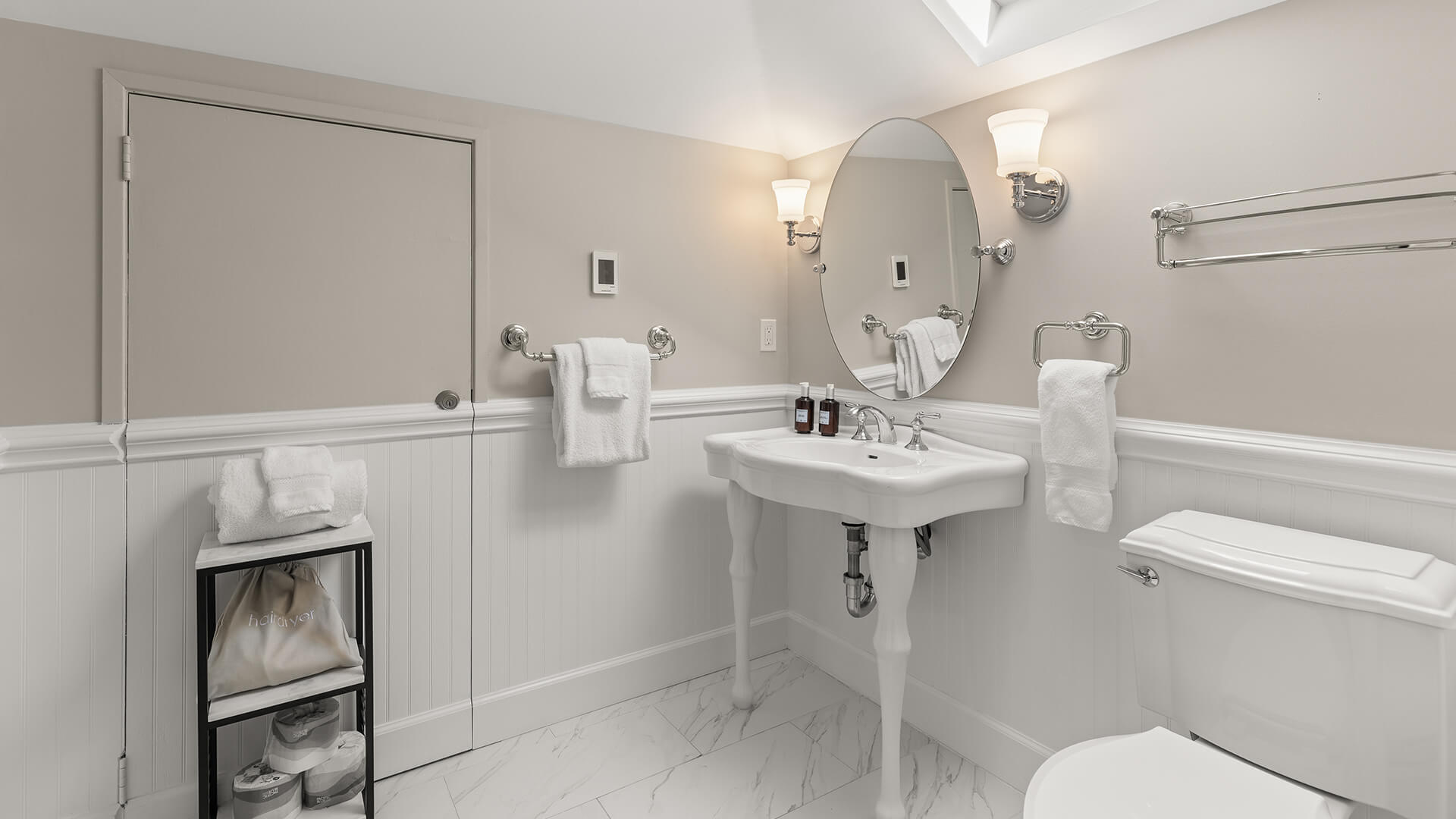 A clean and well-appointed bathroom with a sink, toilet, and marble floor.