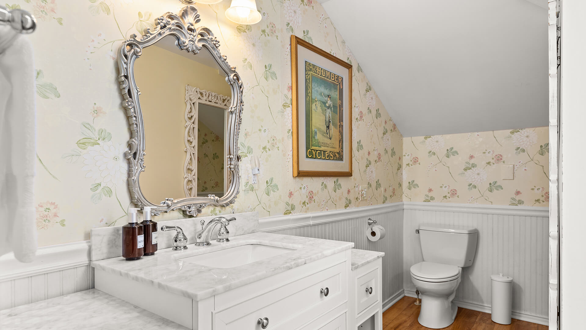 A clean and well-appointed bathroom with a white vanity, marble countertop, and ornate mirror.