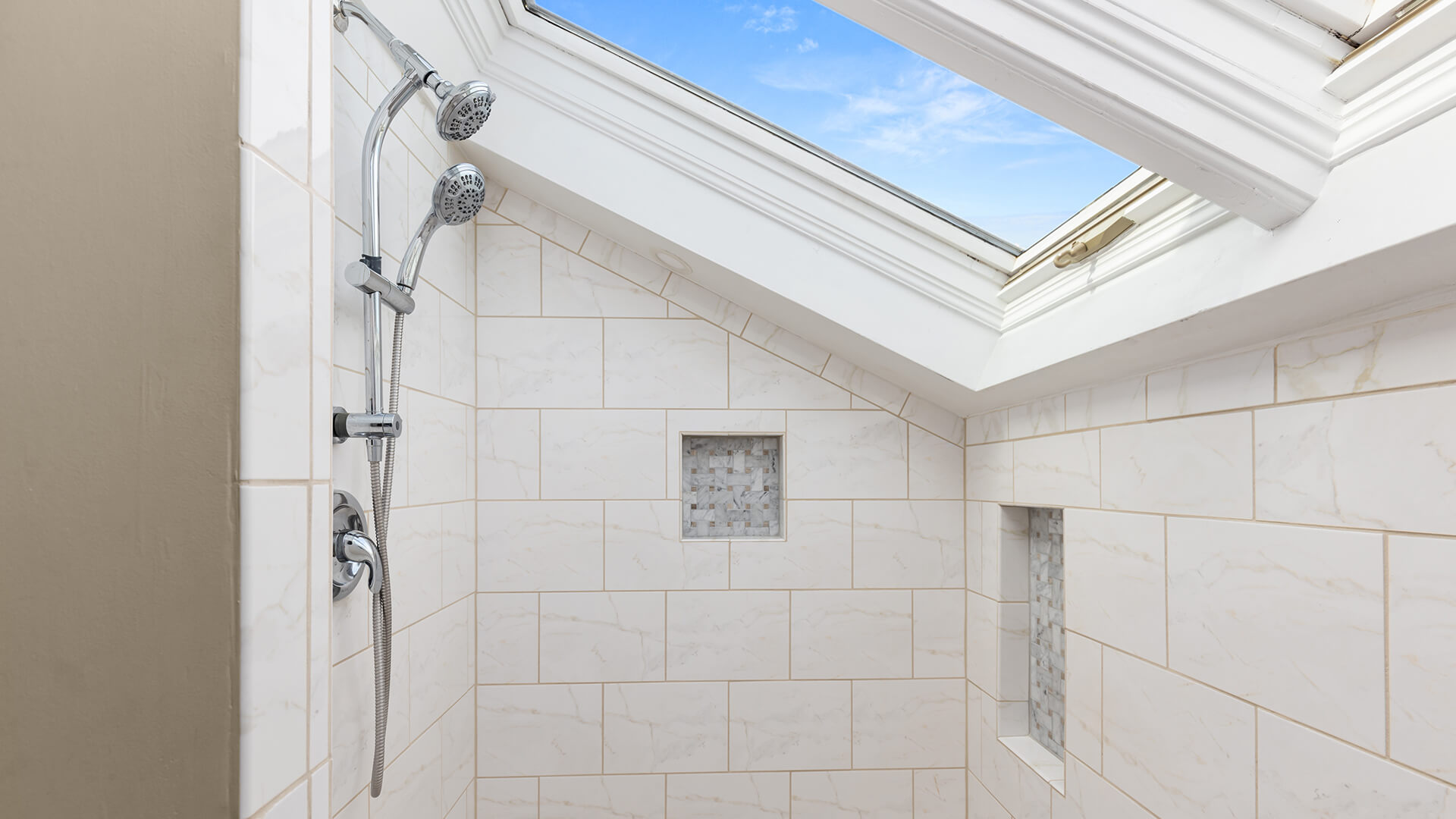 A shower with a skylight and white tile