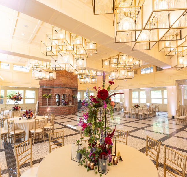 a room with tables and chairs and a vase of flowers