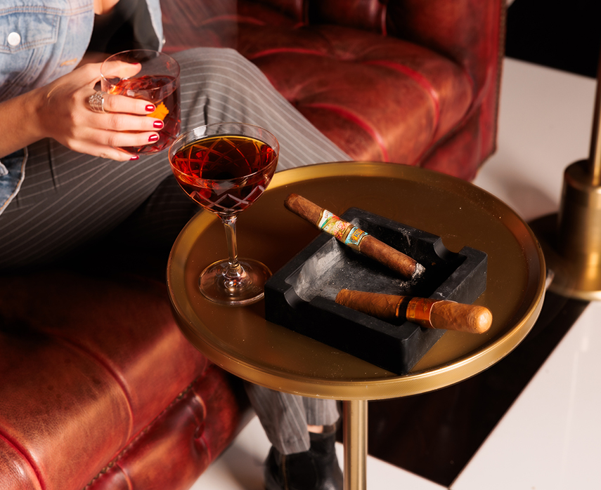 a woman sitting on a couch with a cigar and a glass of wine