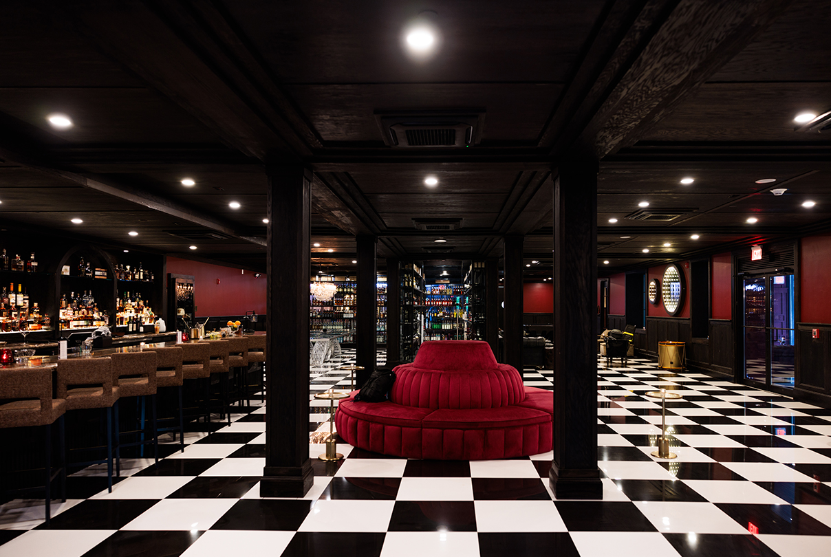 a black and white checkered floor with a red round couch