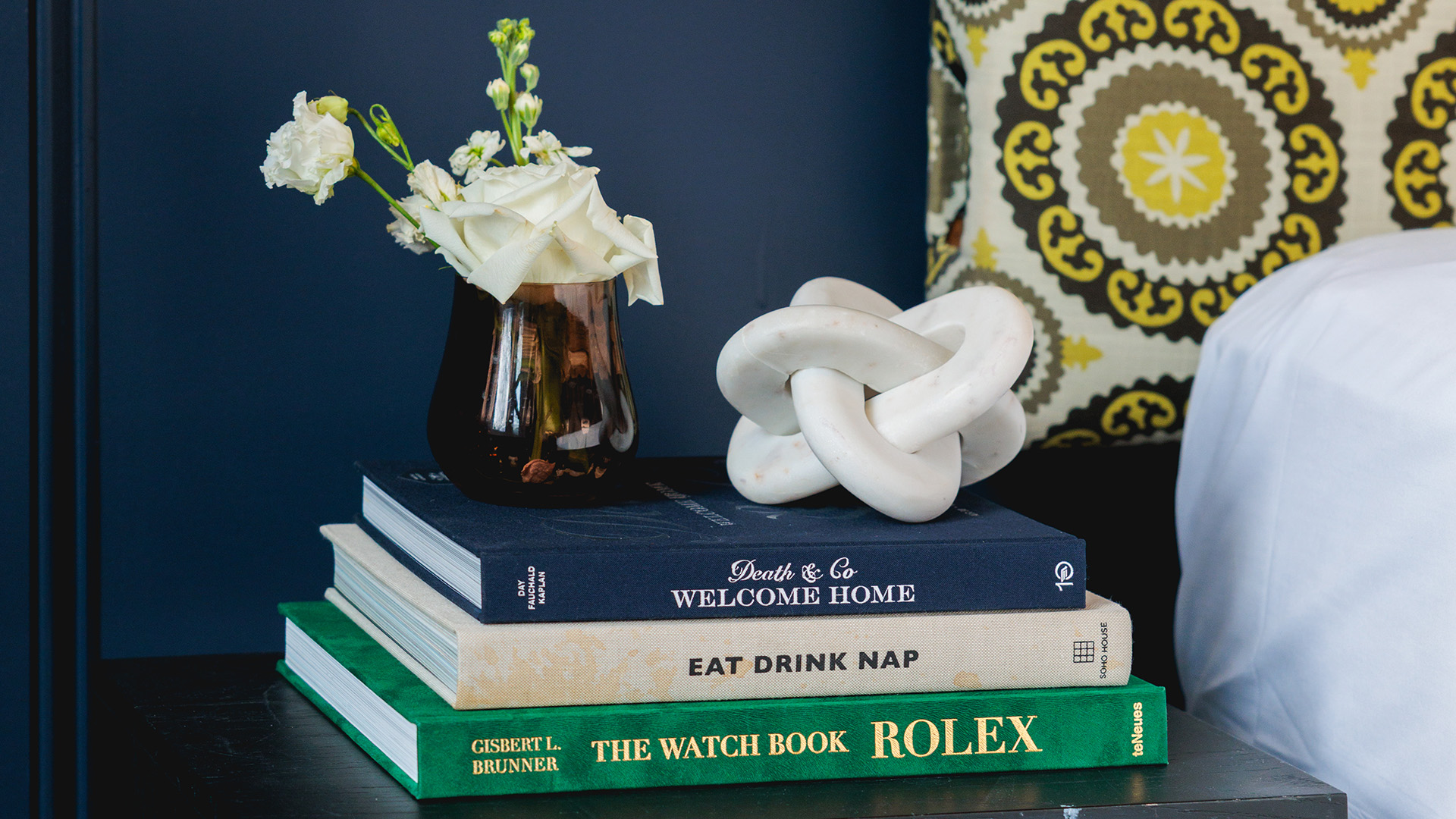 a stack of books with a vase of flowers