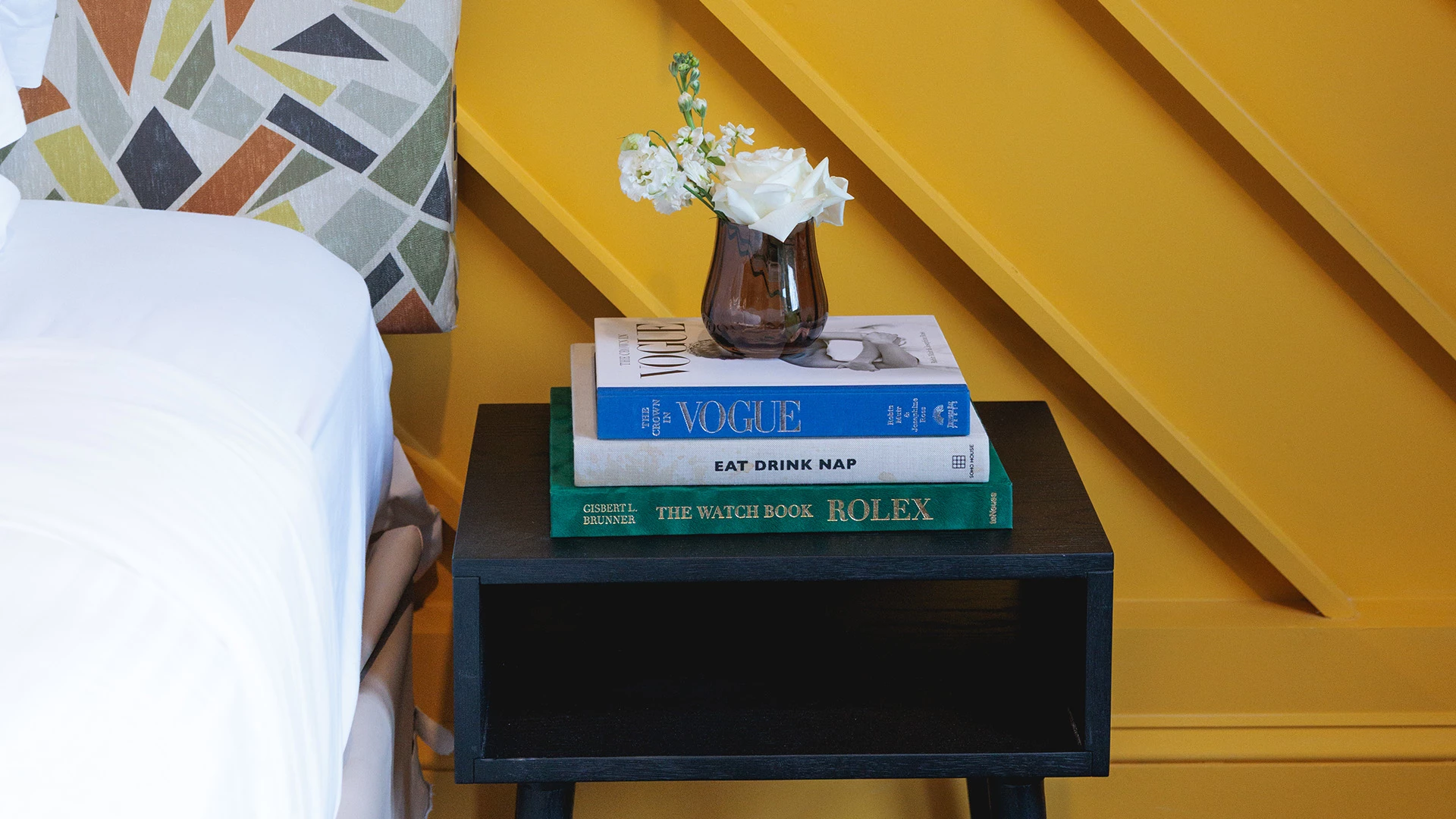 a stack of books with a vase of flowers on top