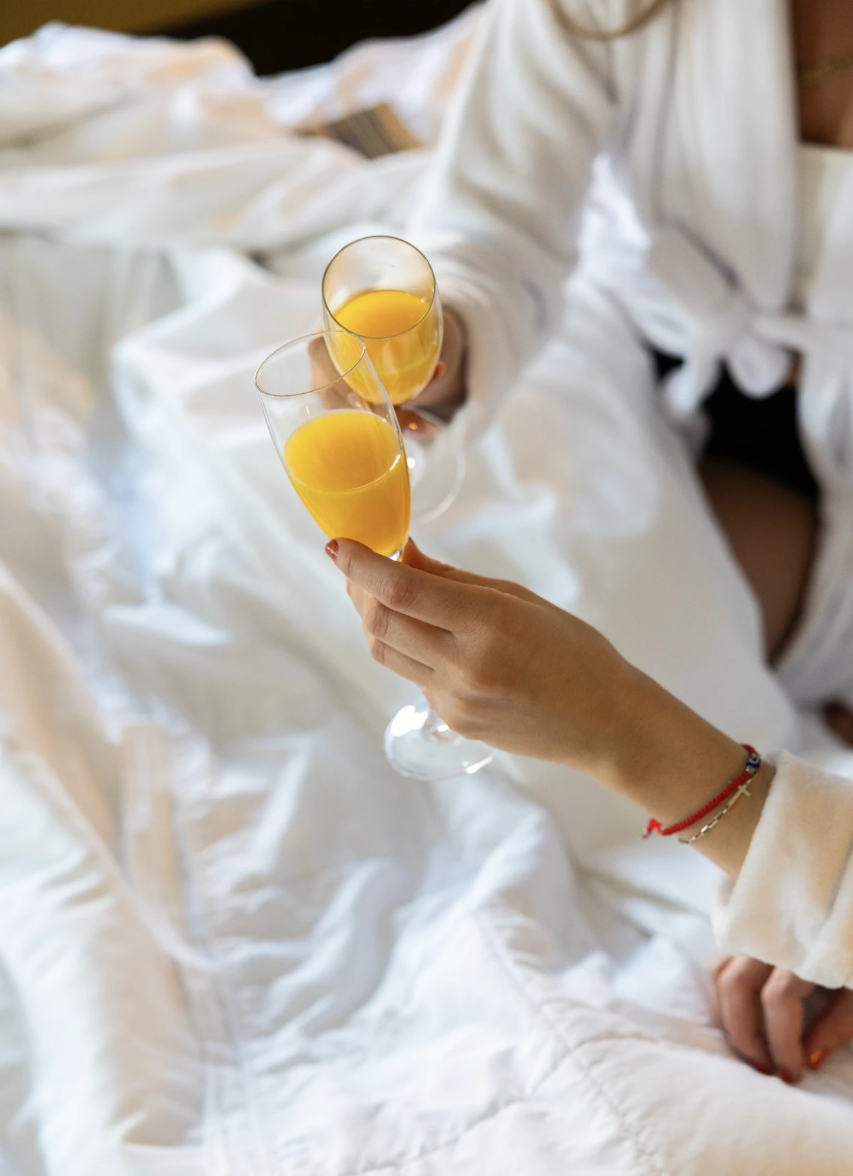 a person holding up two glasses of orange juice
