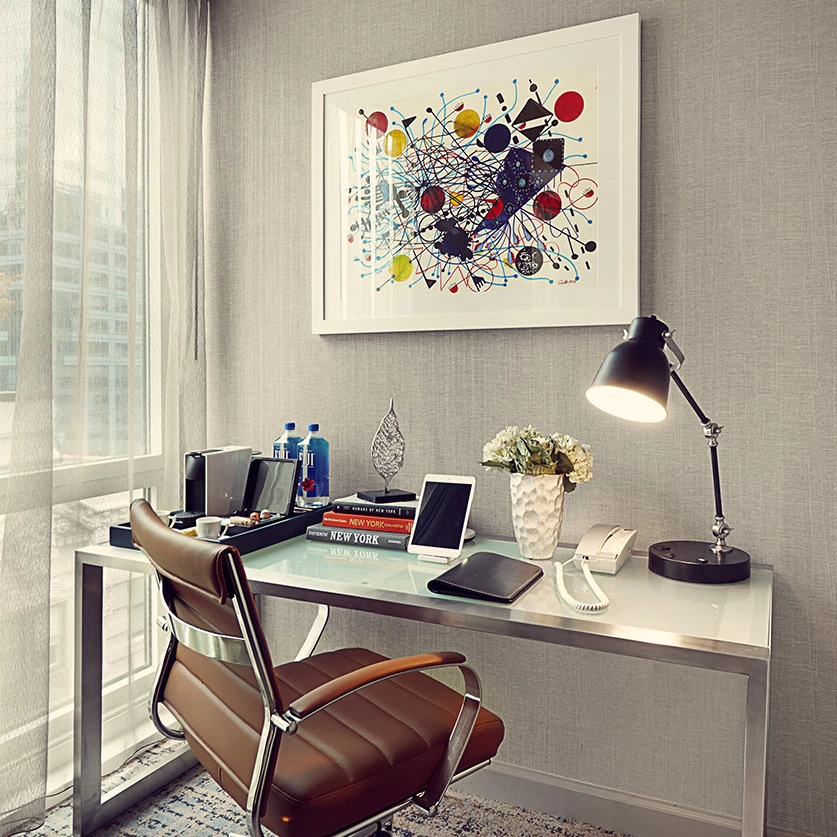 a desk with a lamp and a painting on the wall