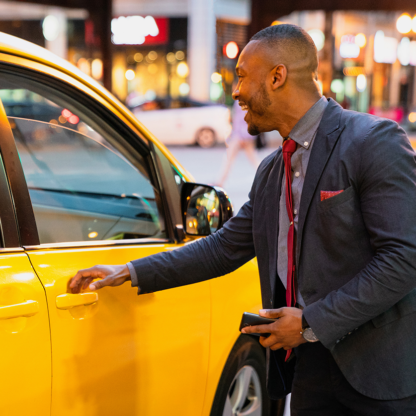 a man in a suit and tie opening a door of a yellow car