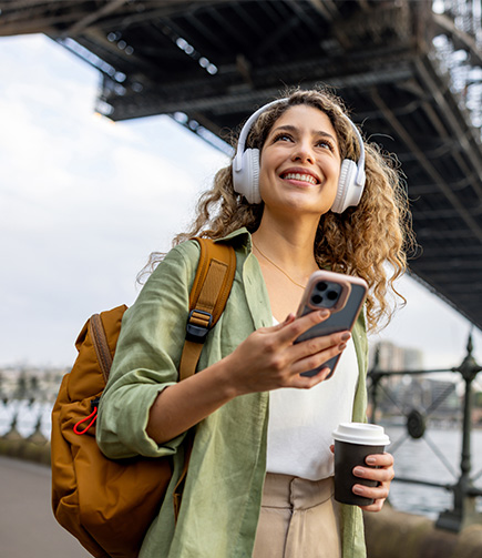 a woman wearing headphones and holding a phone and a cup of coffee